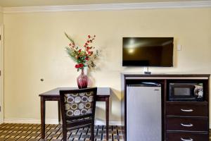 a table with a vase of flowers and a tv at Hacienda Inn in La Puente