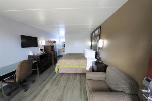 a hotel room with a bed and a desk and chairs at Super 8 by Wyndham Manassas in Manassas