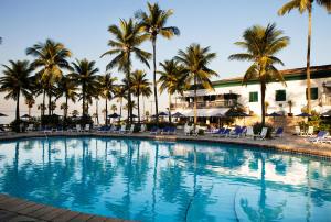 une grande piscine bordée de palmiers et de chaises dans l'établissement Casa Grande Hotel Resort & Spa, à Guarujá