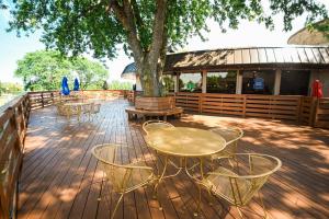 une terrasse en bois avec des tables, des chaises et un arbre dans l'établissement Par 5 Resort, à Mishicot