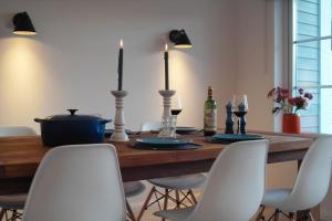 una mesa de comedor con sillas blancas y una botella de vino en Design Ferienhaus am Plöner See Nahe der Ostsee, en Bosau