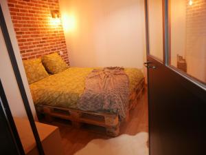 - une chambre avec un lit dans une pièce dotée d'un mur en briques dans l'établissement Maison cœur de ville esprit industriel - Le Loft12, à Châteauroux