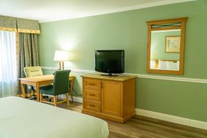 a hotel room with a bed and a desk with a television at Hotel Piccadilly in Fresno