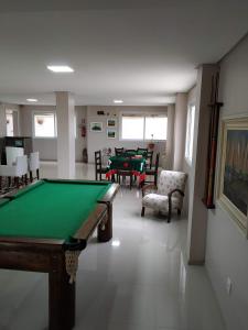 a pool table in a room with two tables and chairs at Hotel Jardim do Mar in Torres