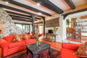 a living room with red furniture and a stone wall at Casa La Ermita in Antigua Guatemala