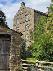 een oud bakstenen gebouw met een hek en een hek bij Wonderfully Scenic and Comfortable Dales Mill Property in West Burton