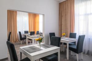 uma sala de jantar com mesas, cadeiras e janelas em Casa Andreea em Braşov