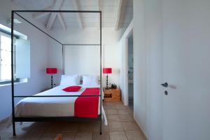 a bedroom with a canopy bed with red pillows at Orloff Resort in Spetses