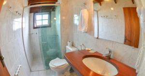 a bathroom with a sink and a shower and a toilet at Hotel Aconchego da Serra in Gramado