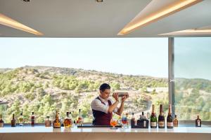 un homme prenant une photo d'un bar avec des bouteilles d'alcool dans l'établissement Princess Sun Hotel, à Kiotari