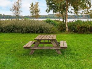 a wooden picnic table in the grass near a lake at 10 person holiday home in Ansager in Ansager