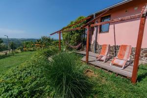 a porch with two chairs and a house at Panorama Vegapansion in Szendehely