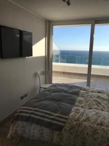 Un dormitorio con una cama y vista al mar. en Departamento Terrazas de Cochoa 1 dormitorio, en Viña del Mar
