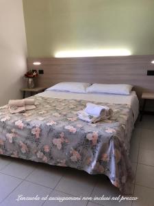 Ohana Apartments Camping Tiglio في سيرمِيوني: غرفة نوم بسرير كبير عليها ورد وردي