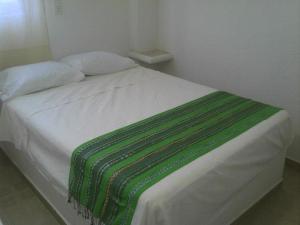 un letto bianco con una coperta verde e bianca di Hotel QUINTA DIAMANTE a Barra Vieja