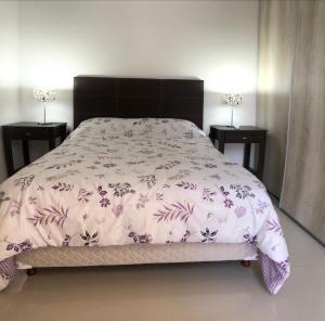 Una cama con un edredón rosa y dos mesitas de noche. en Palermo Apartments, en Buenos Aires