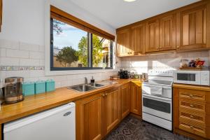 uma cozinha com armários de madeira, um lavatório e uma janela em Coopers Cottage Battery Point em Hobart