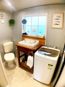 a bathroom with a sink and a toilet and a window at The Little Red Shed in Russell