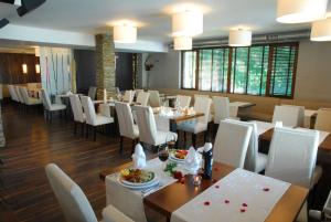a dining room with tables and white chairs at Forest Nook Aparthotel in Pamporovo
