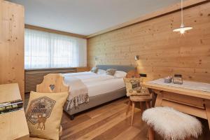 a bedroom with a bed and a wooden wall at Residence Villa Al Sole in Corvara in Badia