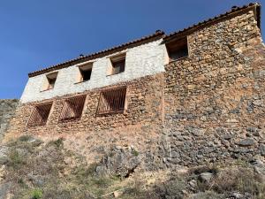 un vieux bâtiment en pierre avec des fenêtres à barreaux sur une colline dans l'établissement Casa Purujosa, à Purujosa