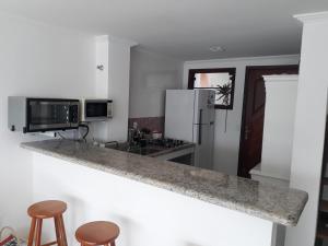 a kitchen with a counter top with a refrigerator and stools at Casa em Angra dos Reis no Paraíso do Condomínio do Engenho in Angra dos Reis