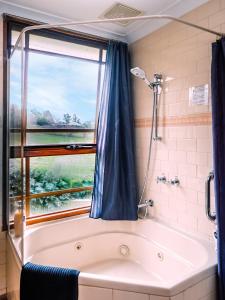 a bathroom with a tub, shower and a window at Amble at Hahndorf in Hahndorf