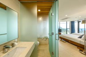 a bathroom with a tub and a bed in a room at Jeju Bom Museum stay in Seogwipo