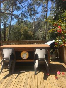 a wooden bench sitting on a deck with two stools at Grampians Nest in Halls Gap