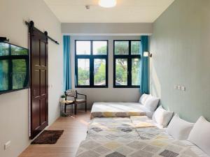 a bedroom with two beds and a window at OYAJI Guesthouse 歐野基民家宿泊 in Tainan
