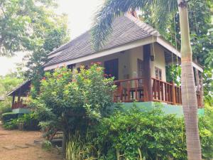 Pai Flora Resort في باي: منزل مع شرفة ونخلة