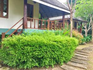 a house with a large green bush in front of it at Pai Flora Resort in Pai