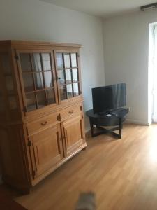 ein Wohnzimmer mit einem großen Holzschrank und einem TV in der Unterkunft Apartment in Duisburg-Rheinhausen in Duisburg