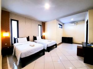a hotel room with two beds and a television at Ganggas Homestay in Jimbaran
