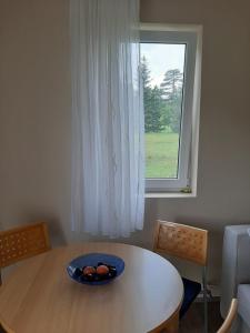 einen Tisch mit einer Obstschale vor einem Fenster in der Unterkunft Apartman Narcis Polje in Divčibare
