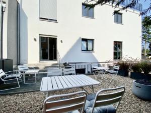 une terrasse avec une table et des chaises devant un bâtiment dans l'établissement modernes Apartment, Terrasse und Garten am Lilienthalpark im Südwesten Berlins, à Berlin