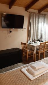 a living room with a table and a television on the wall at Room near the Airport in Pikérmion