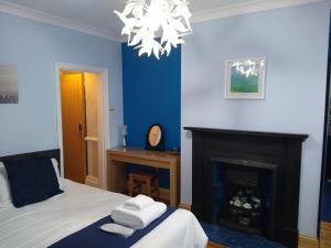 1 dormitorio azul con 1 cama y chimenea en Cromer Guest House, en Bridlington