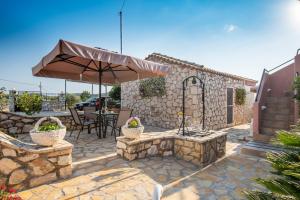 patio con ombrellone, tavolo e sedie di Sofias cottage Razata Argostoli a Razáta