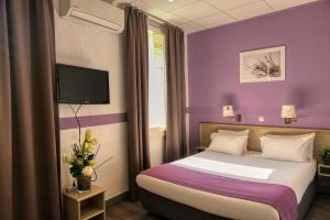 a hotel room with a bed with purple walls at Brit Hotel Le Louvre in Orange