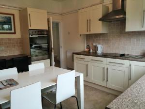 a kitchen with white cabinets and a white table and chairs at Lazy Days in Bournemouth