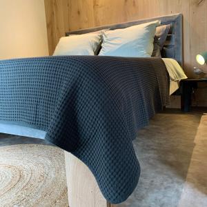a bed with a blue comforter on top of it at Hoogtij°d in Oostvoorne