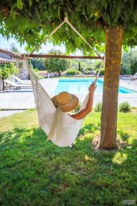 a woman in a hammock under a tree next to a pool at La Fréjade in Lisle-sur-Tarn