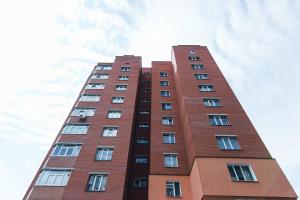 a tall red brick building against a cloudy sky at Apartmens Faraon On Illinskaya New Building 6 floor in Sumy