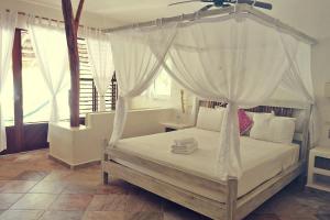 a bedroom with a white bed with a canopy at Almaplena Boutique Hotel in Mahahual
