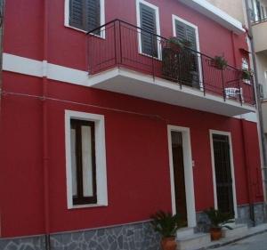 a red building with a balcony on the side of it at Le Stelle Del Tirreno in Falcone +8 photos