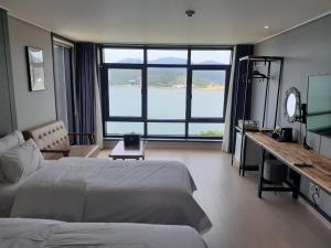 统营市Tongyeong Bridge Hotel的一间卧室，配有一张床、一张书桌和一扇大窗户
