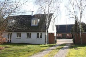 uma casa branca com um telhado preto e uma entrada em Stenbrogård em Harlev