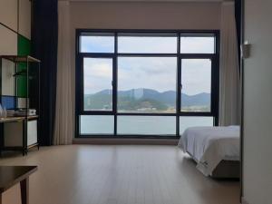 统营市Tongyeong Bridge Hotel的一间卧室设有大窗户,享有水景