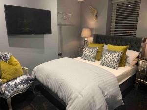 a bedroom with a bed and a tv and a chair at Egremont House - Brighton Rock Rooms in Brighton & Hove